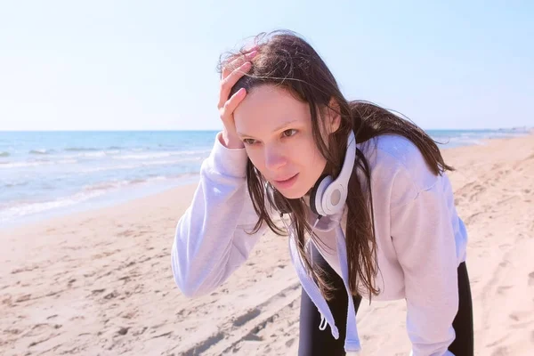 Flicka sluta jogga för att fånga andedräkt sport springa träning hav sand strand hörlurar. — Stockfoto