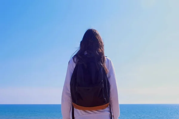 Chica viajero con mochila puestos mira al mar en vacaciones lado vista al aire libre . —  Fotos de Stock