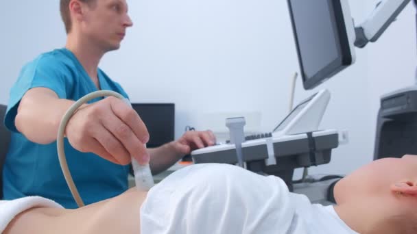 Man doctor making abdominal ultrasound to diagnostic stomach to woman in clinic. — Stock Footage Man doctor making abdominal ultrasound to diagnostic stomach to woman in clinic. Stock Video
