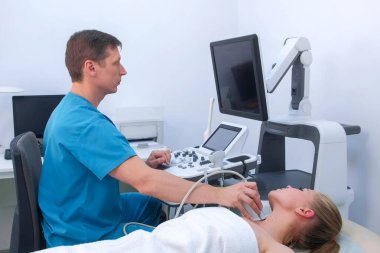 Hasta muayene eden erkek doktor kadın tiroid bezi ultrason tarayıcısı kullanıyor..