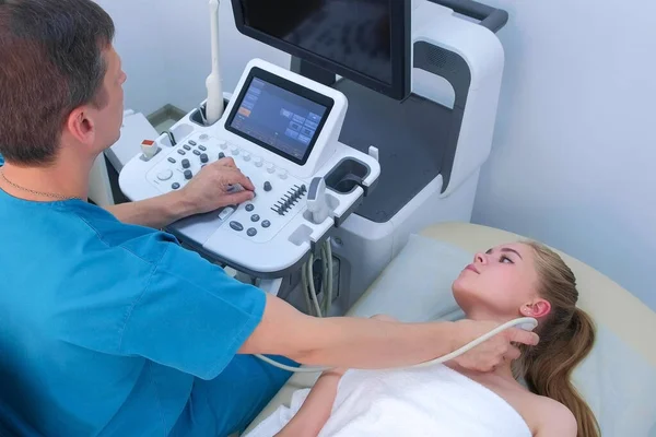 Man doctor examining patients woman thyroid gland using ultrasound scanner.