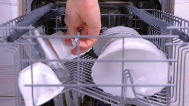 Man is putting a cups in the dishwasher, pushing the basket inside and runnig dishwasher. — Stock Video