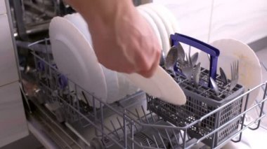 Erkek eli beyaz tabak koyuyor ve bulaşık makinesini kirli beyaz tabaklarla kapatıyor..