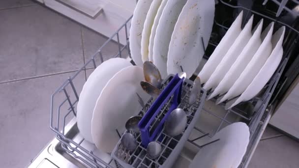 Корзина посудомоечной машины с грязной белой посудой и столовыми приборами на кухне . — стоковое видео