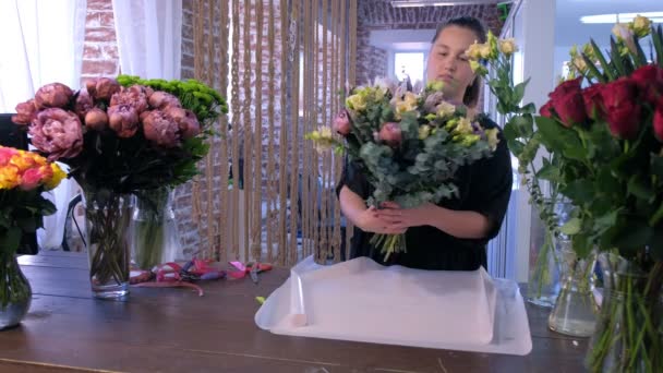 Květinářství žena pracuje balení velké květiny kytice v bílém papíru v květinářství. — Stock video