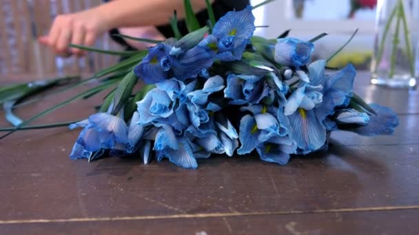 Fiorista donna crea bouquet da fiori di iris blu sul tavolo in vendita nel negozio . — Video Stock