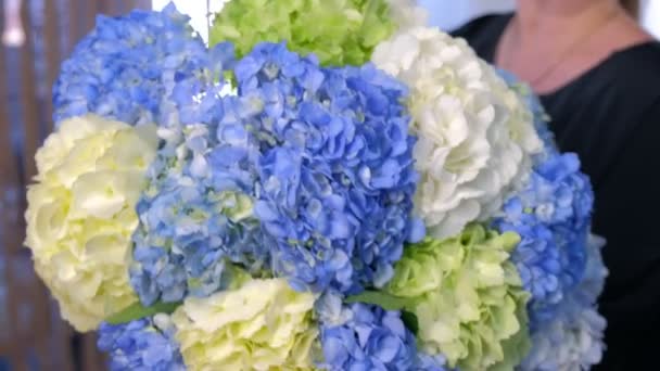 花屋の女性は販売のための店でアジサイの花の巨大な花束を示しています. — ストック動画