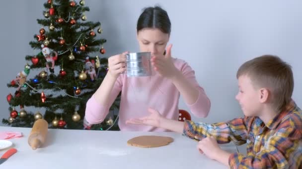 Mamá e hijo están haciendo masa para galletas de Navidad sentados en la mesa . — Vídeo de stock