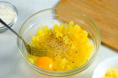 Yumurta karıştıran bir kadın, haşlanmış patates püresiyle draniki pişiren bir kadın, mutfakta krep, yakın plan eller. Tabak hazırlanıyor. Mutfak, mutfak, yemek tarifi. Öğle yemeğinde geleneksel Rus yemeği..