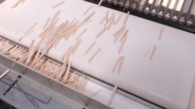 Taşıyıcı banttaki ahşap dondurma çubuklarını düzenleyen otomatik makine işleme. Üretim hattı olan makine ekipmanları. Sanayi üretimi: Ahşap ürünler, kereste, fabrikada kereste..