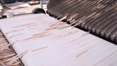 Taşıyıcı banttaki ahşap dondurma çubuklarını düzenleyen otomatik makine işleme. Üretim hattı olan makine ekipmanları. Endüstriyel üretim ahşap ürünler, kereste, fabrikada kereste.