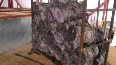 Metal yapı, ahşap fabrikasındaki sıcak su odunlarına batırılmış yığın halinde duruyor. Ahşap ürünler, kereste, atölyede kereste üretimi. Otomatik endüstriyel makine hattı.