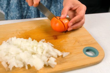 Aşçı kadın, mutfaktaki tahta kesme tahtasının üzerinde domates pişiriyor. Taze sebze malzemeleri, aşçılık teknikleri, ev yapımı aşçılar sağlıklı yemekler hazırlamak, keskin baharatlar..