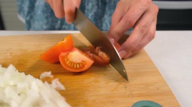 Aşçı kadın, mutfaktaki tahta kesme tahtasının üzerinde domates pişiriyor. Taze sebze malzemeleri, aşçılık teknikleri, ev yapımı aşçılar sağlıklı yemekler hazırlamak, keskin baharatlar..