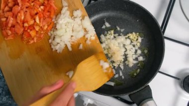 Aşçı kadın tavaya doğranmış soğan ekliyor. Mutfakta da sarımsak ve yağ var. Mutfak teknikleri, ev yapımı sağlıklı yemek hazırlama, yemek yemeği, mutfak, yemek için baharat iyi tat..