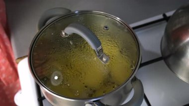 Kadın tencere kapağını suyla kaynatılmış patatesle açıyor, mutfakta yemek pişiriyor. Mutfak, aşçı, ev yemeği, yemek tarifi, çiğ sebze malzemeleri, ürünler..