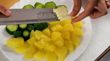 Beyaz tabakta turşunun yanında haşlanmış patatese tereyağı koyan kadın, yakın plan. Mutfak, aşçı, aşçı, ev yemeği, tarif, taze malzemeler, ürün konsepti..