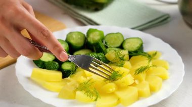 Kadın haşlanmış patates, tereyağı, turşu ve beyaz tabakta taze dereotu ile servis edilen yemekleri yer. Mutfak, aşçı, aşçı, ev yemeği, tarif, taze malzemeler, ürünler..