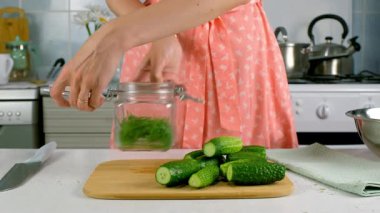 Kadın cam kavanoza salatalık koyuyor mutfakta turşu pişiriyor, elleri yakın plan, elleri yakın plan. Mutfak, aşçılık, aşçılık, ev yemeği, yemek tarifi, taze organik malzemeler konsepti..