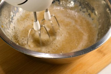 Fırıncı, elmalı püre jelatini elektrikli mikser kullanarak metal kasede karıştırıyor. Mutfak mutfağı, yemek pişirme hamur işi. Şekerli marşmelov hazırlıyorum. Ev yapımı elma reçeli..