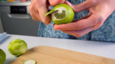 Kadın elleri evde mutfakta bıçak kullanarak kireç meyvesi soyuyordu. Malzeme tarifi aşçılığı. Turunçgil tatlısı, ev yapımı taze içecek, Brezilya limonatası hazırla..