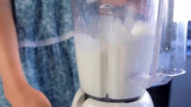 Nane, yoğunlaştırılmış süt, karıştırıcıda limon suyu karıştıran bir kadın evde mutfakta Brezilya limonatası pişiriyor. Yemek tarifi aşçısı. Turunçgil meyveli ev yapımı tatlı hazırla..