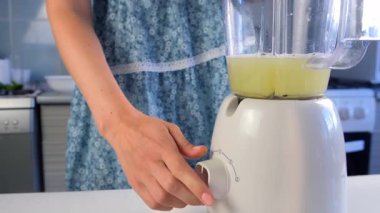 Nane, yoğunlaştırılmış süt, karıştırıcıda limon suyu karıştıran bir kadın evde mutfakta Brezilya limonatası pişiriyor. Yemek tarifi aşçısı. Turunçgil meyveli ev yapımı tatlı hazırla..