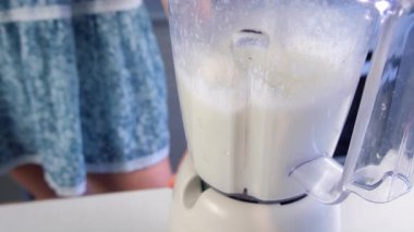 Nane, yoğunlaştırılmış süt, karıştırıcıda limon suyu karıştıran bir kadın evde mutfakta Brezilya limonatası pişiriyor. Yemek tarifi aşçısı. Turunçgil meyveli ev yapımı tatlı hazırla..