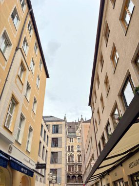 A view up at the various architectural styles of different eras of buildings in the historical part of Munich while walking along quiet, cozy streets on a cloudy rainy summer day.