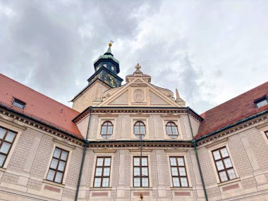 A view up at the various architectural styles of different eras of buildings in the historical part of Munich while walking along quiet, cozy streets on a cloudy rainy summer day.
