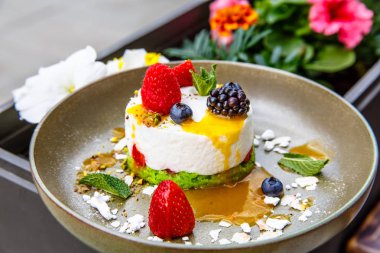 Tatlı cheesecake çilek (böğürtlen, ahududu, çilek, yaban mersini) ile bir plaka üzerinde yatıyor.