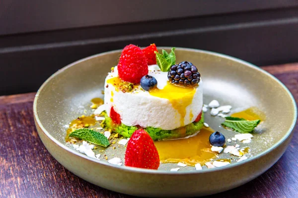 Tatlı cheesecake çilek (böğürtlen, ahududu, çilek, yaban mersini) ile bir plaka üzerinde yatıyor.