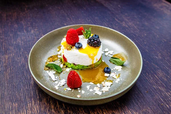 Tatlı cheesecake çilek (böğürtlen, ahududu, çilek, yaban mersini) ile bir plaka üzerinde yatıyor.