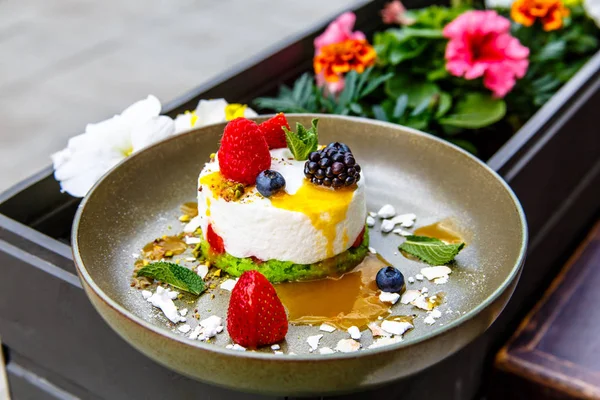 Tatlı cheesecake çilek (böğürtlen, ahududu, çilek, yaban mersini) ile bir plaka üzerinde yatıyor.