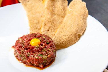 Bıldırcın yumurta ve ekmek cips yalanlarıyla beyaz tabakta klasik biftek tartar.