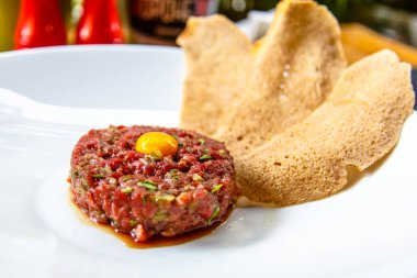 Bıldırcın yumurta ve ekmek cips yalanlarıyla beyaz tabakta klasik biftek tartar.