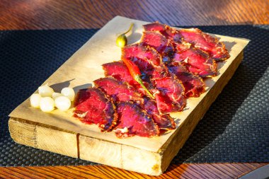 Dilimleri sığır sarsıntılı (jambon, pastırma, leke, prosciutto) biber tahtada vardır