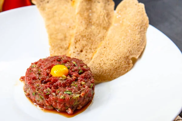 Bıldırcın yumurta ve ekmek cips yalanlarıyla beyaz tabakta klasik biftek tartar.