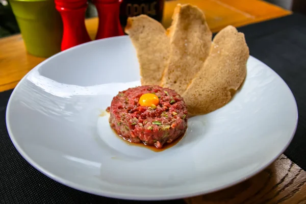 Bıldırcın yumurta ve ekmek cips yalanlarıyla beyaz tabakta klasik biftek tartar.