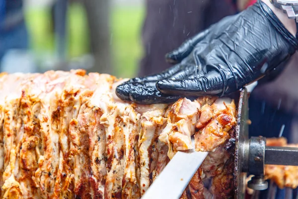 The chef cooks Shawarma (Doner kebab) on the spit and cut it into portions.