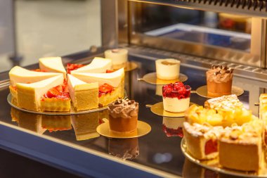 Bir pastane tezgahın üzerine birçok farklı kek vardır.