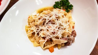 Fettuccine makarna etli açık soslu beyaz bir tabak içinde yatıyor