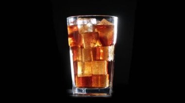 Cola kabarcıkları ile buz cam içine dökülür. Siyah arka plan