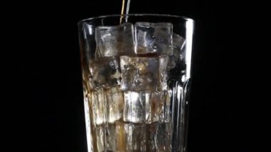 Cola kabarcıkları ile buz cam içine dökülür. Siyah arka plan
