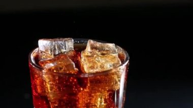 Cola kabarcıkları ile buz cam içine dökülür. Siyah arka plan
