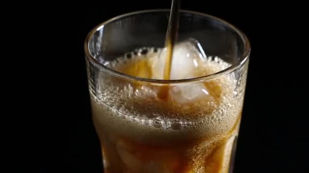 盛有气泡的可乐倒进了一杯冰里 黑色背景 — 图库视频影像