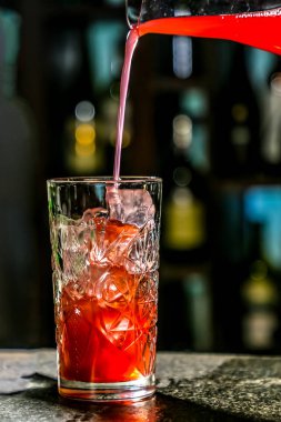 Barmen kırmızı meyve suyu veya meyve suyu bir kokteyl cam kap içine dökülen