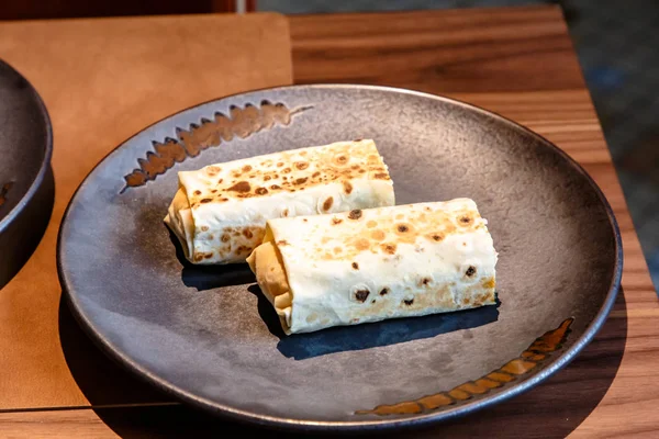 Die Shawarma ist in Fladenbrot eingewickelt, zwei Stück liegen auf einem Teller — Stockfoto