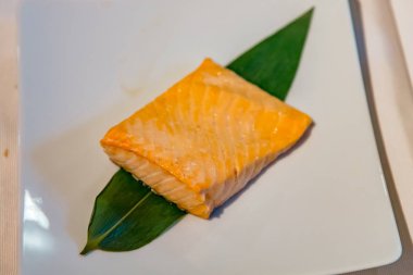 Bir parça somon buğulanmış bir tabak tabak tabak tabak tabak tabak tabak tabak tabak üzerinde yatıyor