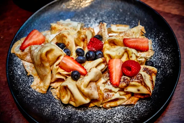 I frittelle con bacche (i mirtilli e le fragole) sono versati — Foto Stock